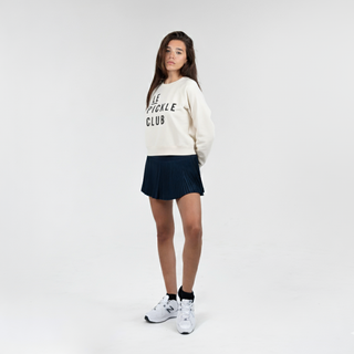 Person wearing a white sweatshirt with text and a navy skirt on a white background