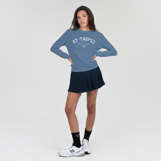 Woman wearing a blue 'St-Tropez' sweatshirt and black skirt on a white background