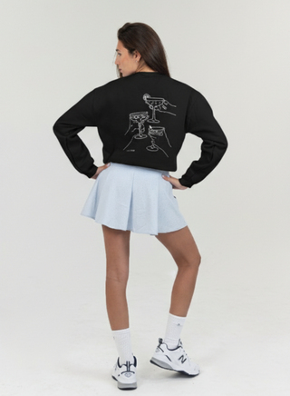 Person wearing a black sweatshirt with a design and light blue skirt on a white background