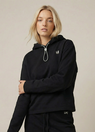 Woman wearing a black hoodie and skirt set with a LPC  on a beige background