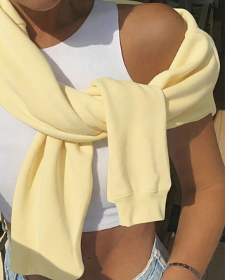 Person wearing a light yellow scarf over a white top