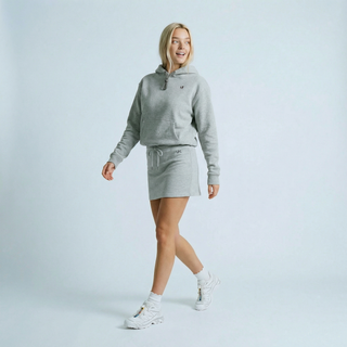 Woman wearing a gray hoodie and skirt set on a light blue background