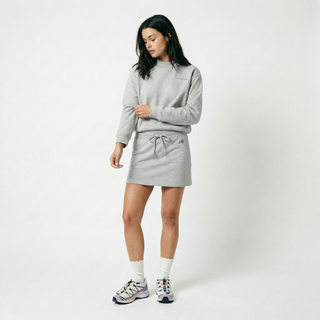 Woman wearing a gray sweatshirt and skirt set on a white background