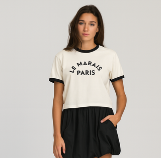 Woman wearing a white t-shirt with 'Le Marais Paris' text and black skirt on a gray background