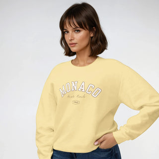 Woman wearing a yellow sweatshirt with 'MONACO' text on a white background