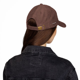 Person wearing a brown cap and black denim jacket on a white background