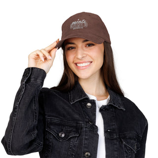 Woman wearing a brown cap with text, smiling against a white background