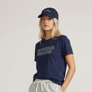 Woman wearing a navy t-shirt, gray shorts, and blue sneakers on a plain background