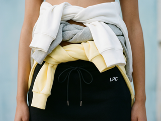 Person holding a stack of folded clothes with 'LPC' branding.