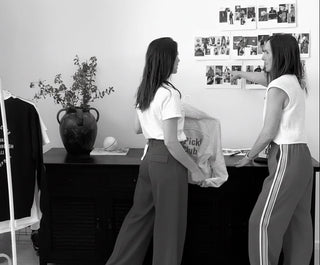 Co-founders  in a room with a black dresser, a plant, and a rack of clothes.