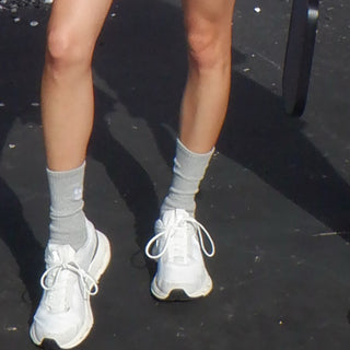 White sneakers and gray socks on a black surface